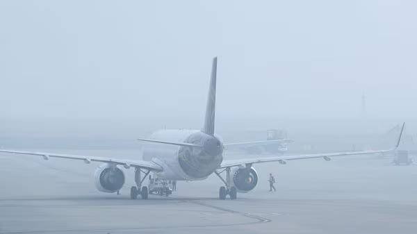 Commercial aircraft taxiing slowly on runway in low visibility winter conditions in India