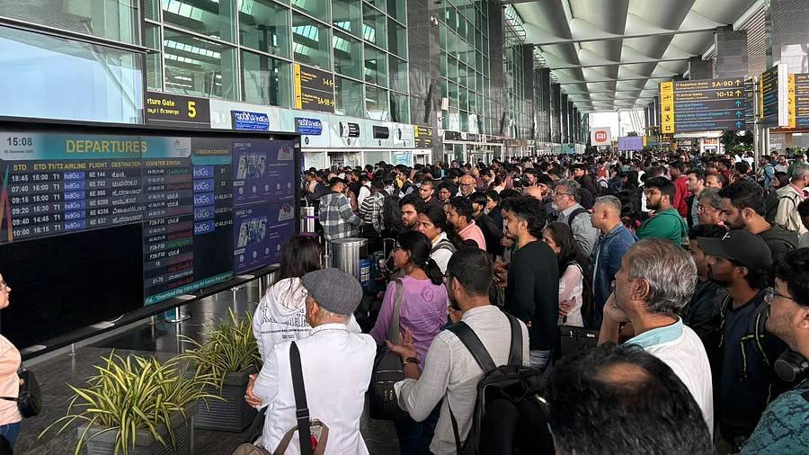 Passengers monitoring departure screens showing multiple IndiGo flight delays.
