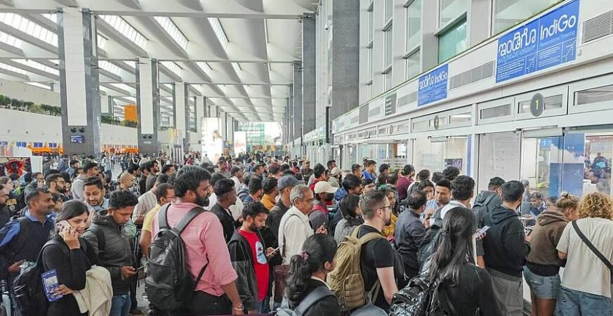Passengers waiting in long queues at an Indian airport due to IndiGo flight delays and cancellations.