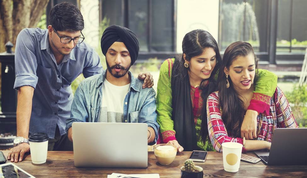 Young Indian entrepreneurs discussing ideas in a startup workspace.