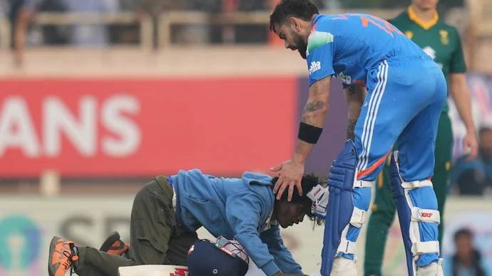 Fans cheering for Virat Kohli in a packed stadium after his milestone